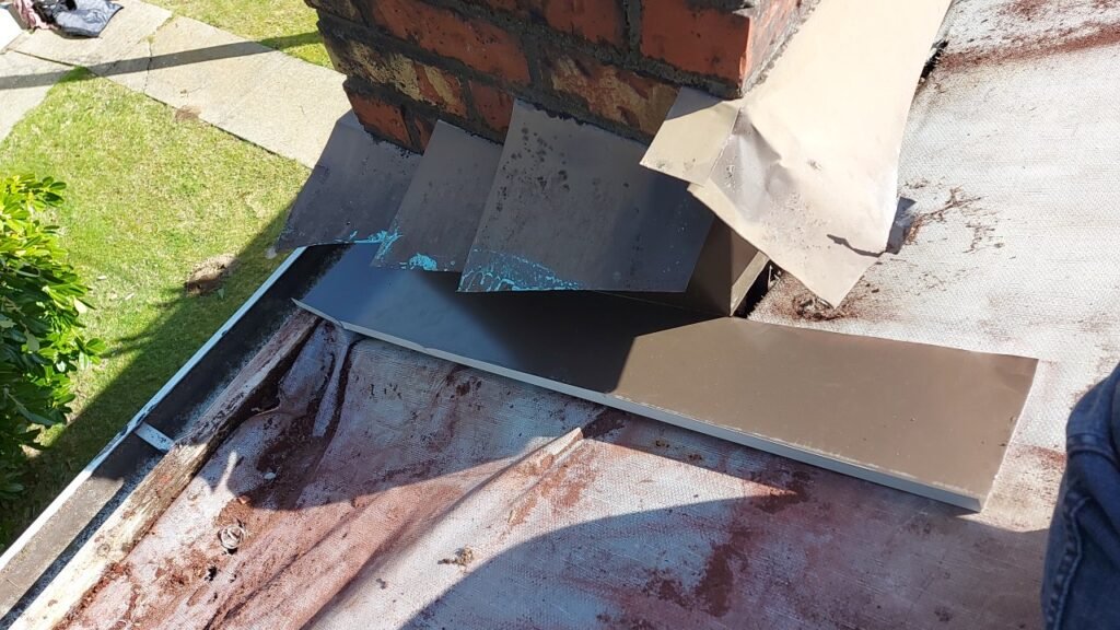 New side pan flashing with a bent containment lip installed at a chimney in Langley.