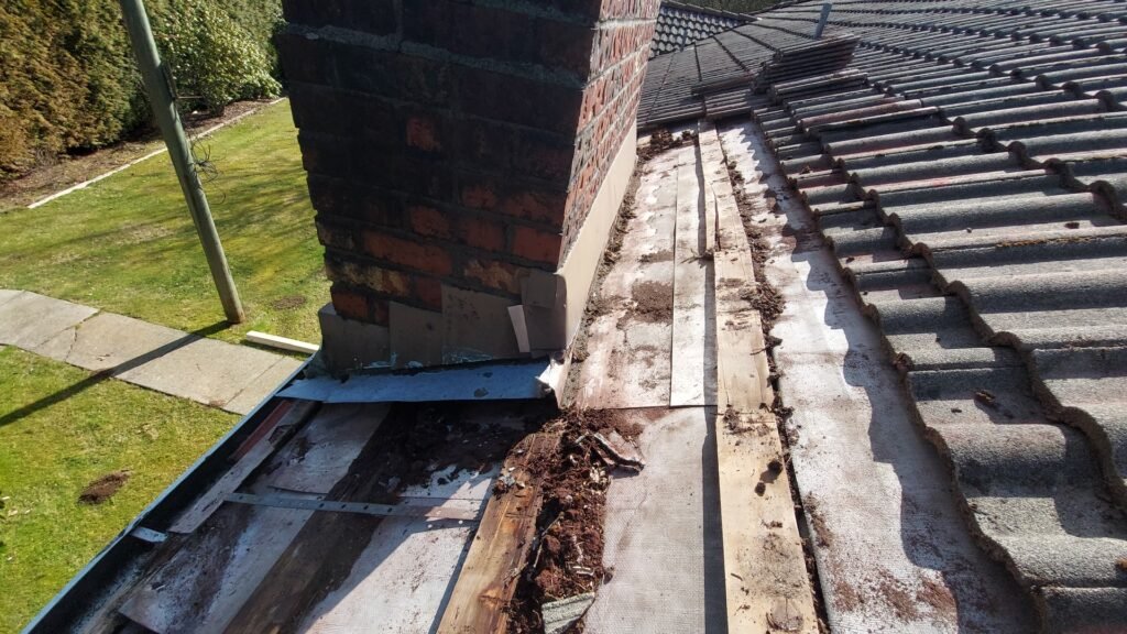 Chimney on a Langley tile roof with the tiles lifted to reach the old pan flashing.
