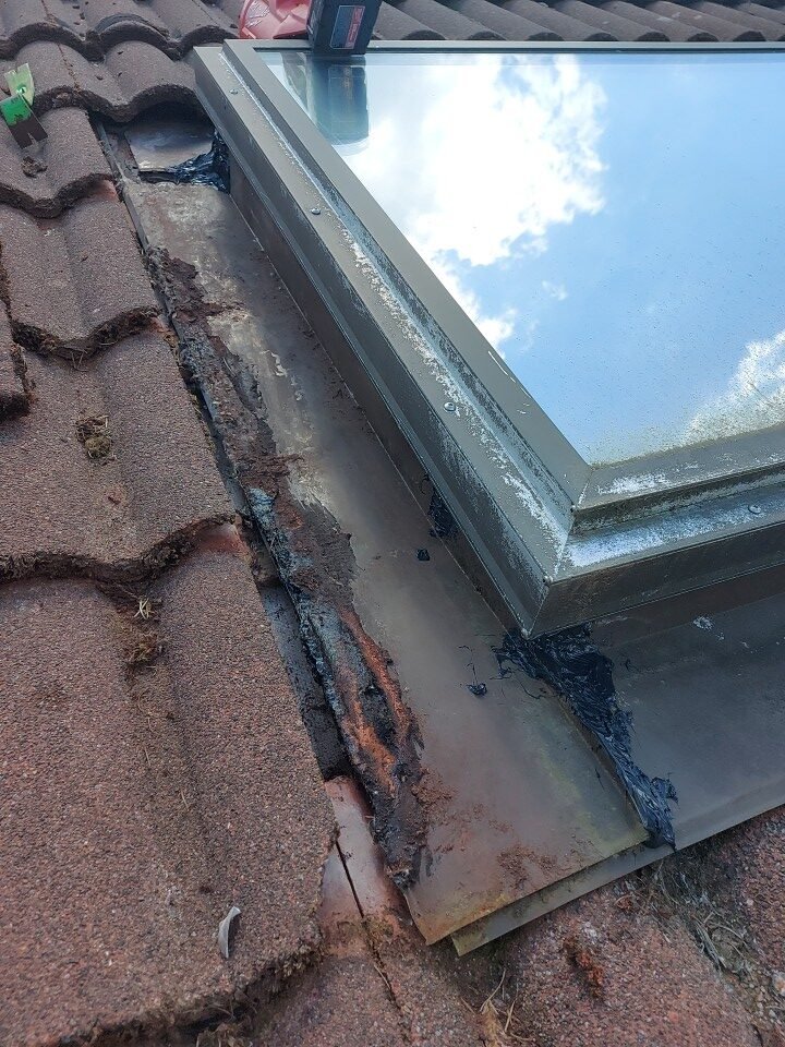 Fresh caulking sealing the pan flashing corners next to the skylight on a Port Moody tile roof.