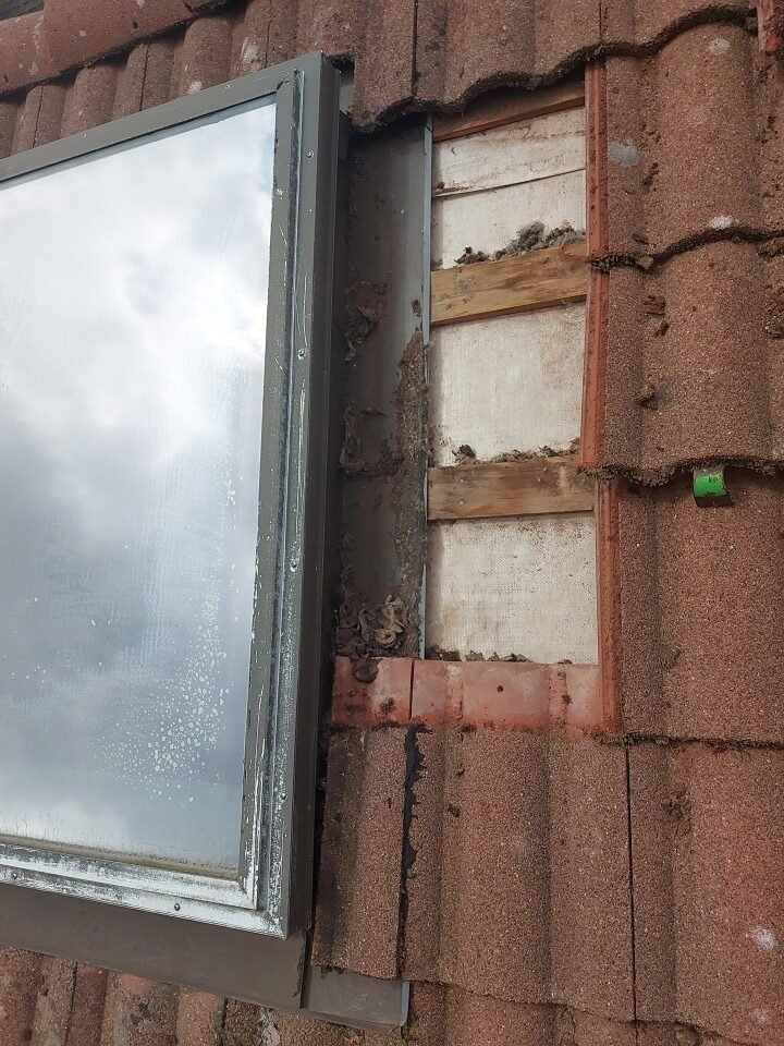 Concrete roof tiles removed beside a leaking skylight to expose the pan flashing in Port Moody.