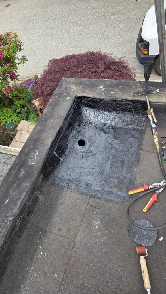 New roof drain installed with the first ply base layer patched around it on a torch-on roof in New Westminster.
