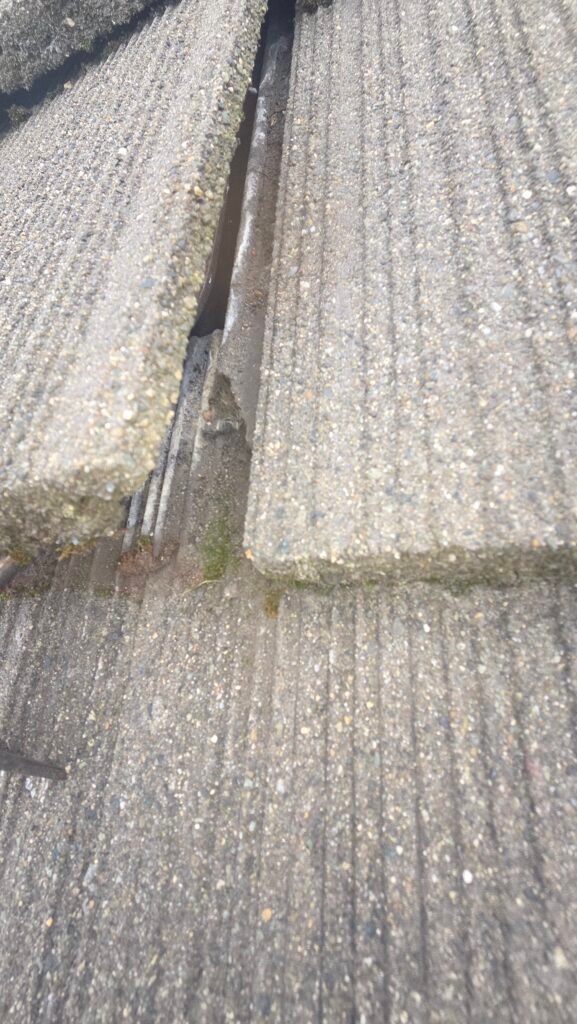 A broken bottom water channel on a tile roof, broken in the area still overlapping the tile below, in Burnaby.