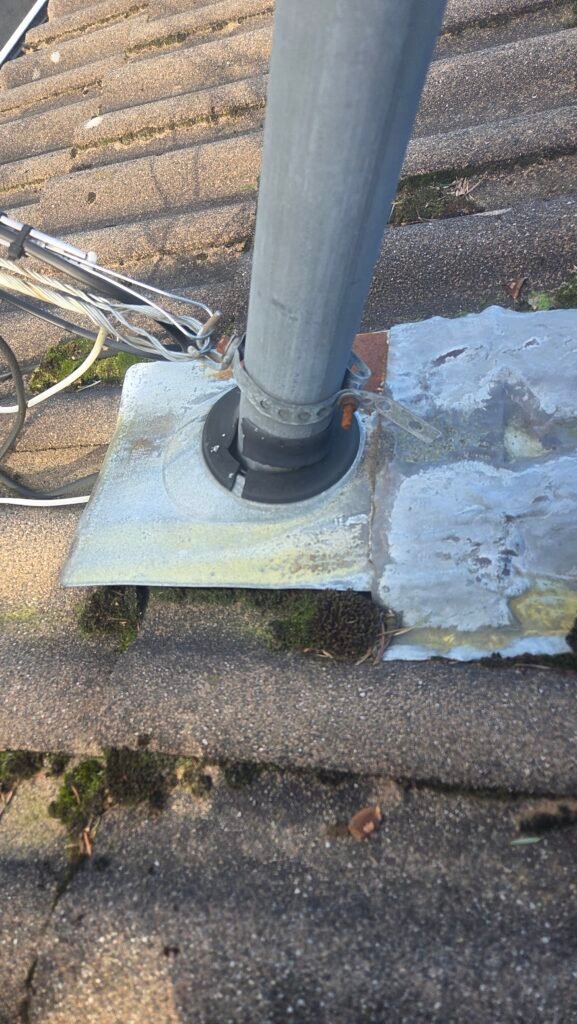 A torn electrical service mast boot with a flat, solid flange that does not conform to the contoured tiles on a roof in Chilliwack.