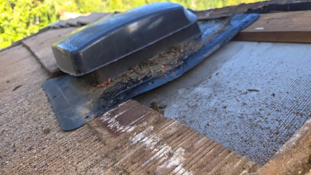 Side view of a plastic roof vent nailed to the batten at the back and resting on tile at the front, with the middle of the flange unsupported.