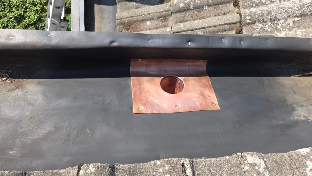Hidden Gutter Drain Leak on a Coquitlam Tile Roof: Why the Drain Goes Over the Membrane 4 New three inch copper drain fastened down on top of the cleaned EPDM membrane in a hidden gutter.
