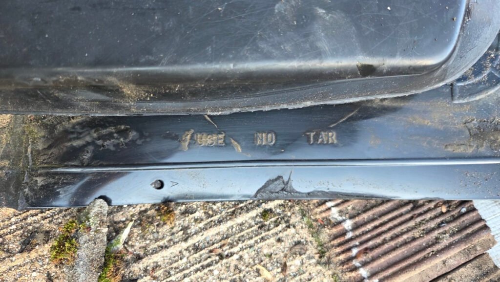 The words USE NO TAR moulded into the flange of a plastic roof vent that had been sealed with roof mastic.